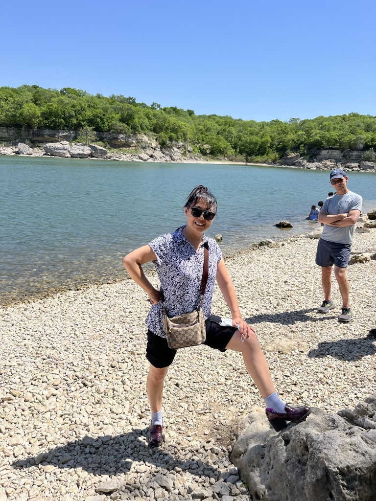 Xiaoyu stands with one foot up on a rock in the same location